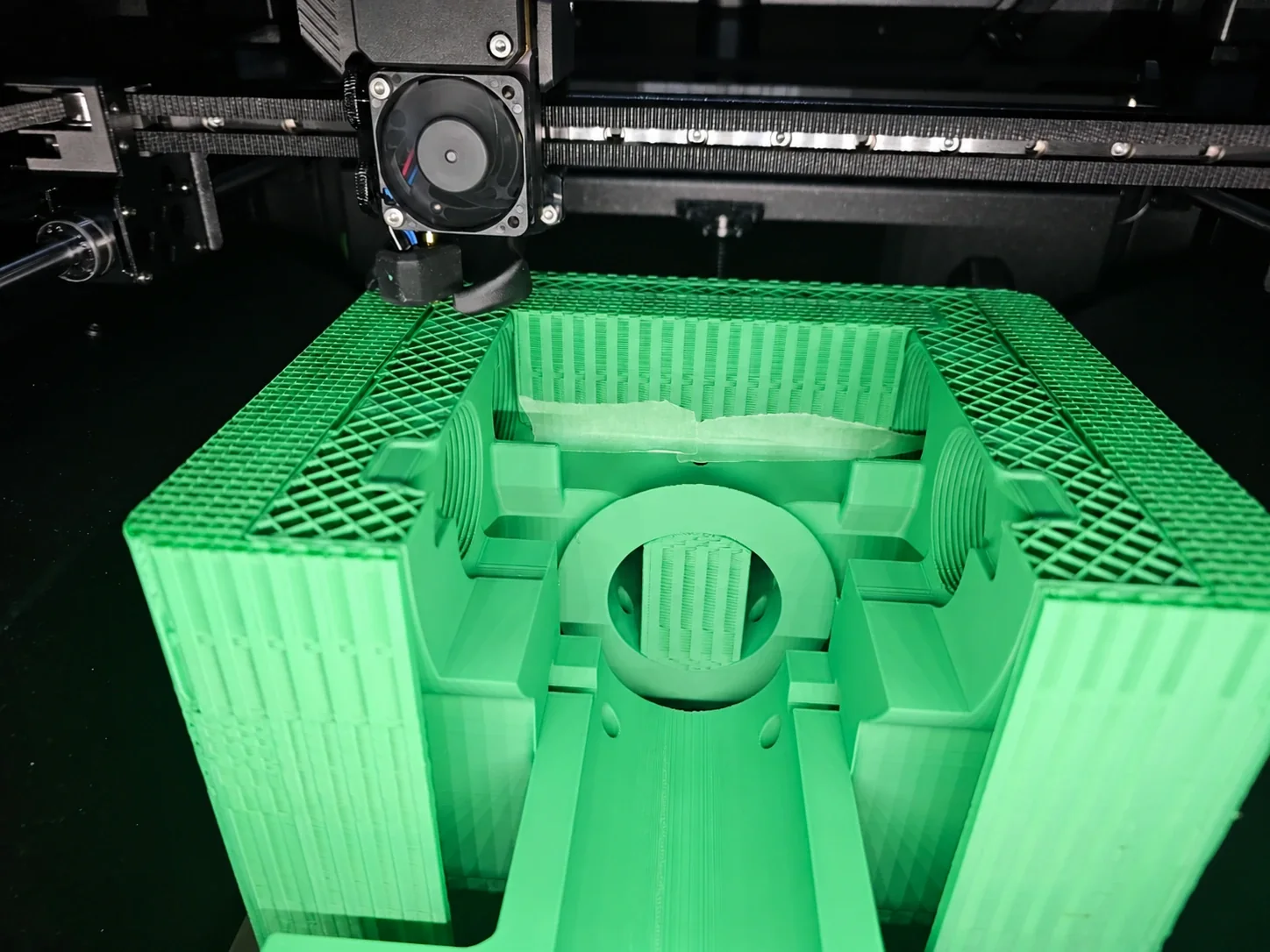 Green model being 3D printed, with its internal structure visible beneath the printer head