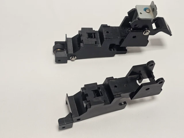 Two black cutter bodies on a light surface, one assembled with metal brackets and hardware