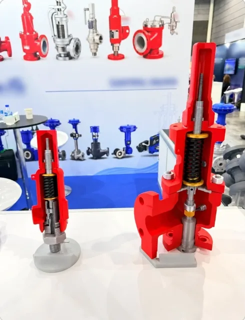 Red valve cutaway models on a trade show display counter